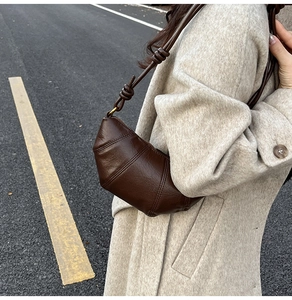 Detail of dark brown quilted croissant bag with knotted strap and gold hardware