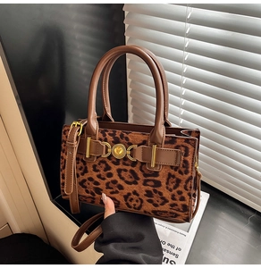 Detail of leopard print crossbody bag featuring golden hardware and leather handle