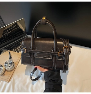 Dettaglio della borsa marrone scuro vintage con cuciture bianche e fibbia in ottone