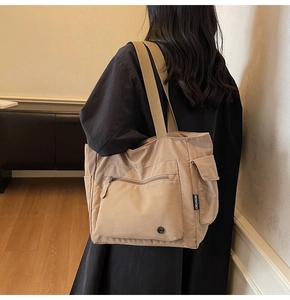 Close-up of khaki canvas tote bag featuring large front zipper and utility side pocket
