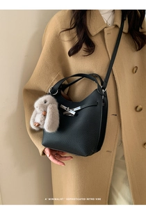Detail of black pebbled leather bucket bag with silver twist lock and plush rabbit charm
