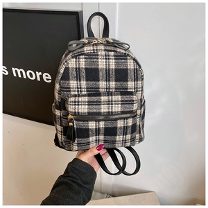 Close-up of black and white checkered tweed fabric texture and gold zippers on backpack