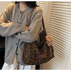 Detailed view of leopard print tote bag with brown plush bear charm and synthetic leather trim