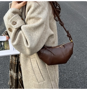 Detail of dark brown leather crescent bag with unique knot shoulder strap and stitching