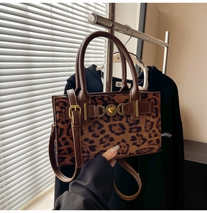 Detailed view of leopard print handbag featuring a gold heart clasp and leather handle