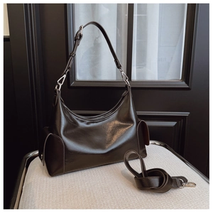 Detail view of dark brown leather hobo bag with side pocket on a cream textured chair
