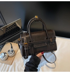 Dettaglio borsa in pelle marrone scuro con cuciture bianche e fibbia in bronzo antico