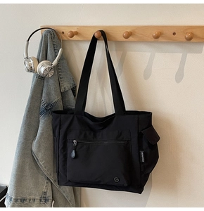 Close-up of black nylon tote bag showing zipper pocket and branded Chuangmi woven label