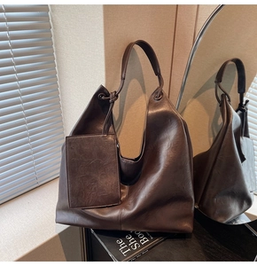 Detail of vintage dark brown faux leather tote bag with small hanging pouch on books