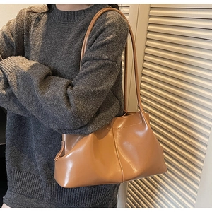 Detail of camel brown pleated tote bag with smooth texture and long shoulder straps