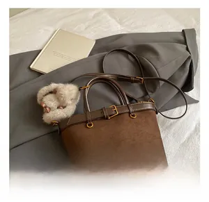 Detail showing vintage brown suede bucket bag with leather buckle and plush charm on clothing