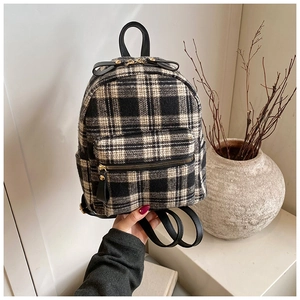 Close-up of black and white checkered wool fabric and leather zipper detail on backpack