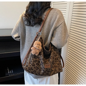 Detailed view of leopard print tote bag with brown leather straps and cute bear charm