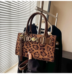 Detail of leopard print handbag with golden heart lock and brown leather handle