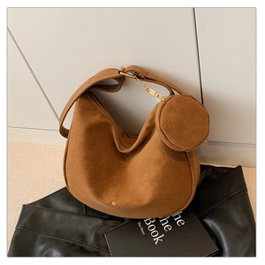 Close-up of caramel suede crescent tote bag with mini gold logo and matching pouch