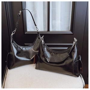 Close-up of black glossy PU leather texture and silver metal hardware on tote bag