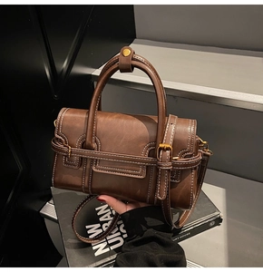 Dettaglio borsa vintage marrone con cuciture a contrasto e fibbia in metallo dorato lucido