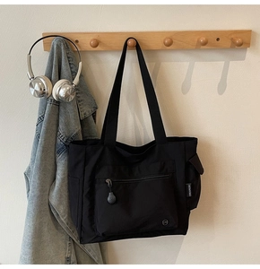 Detail view of large black canvas tote bag with functional pockets and woven logo label