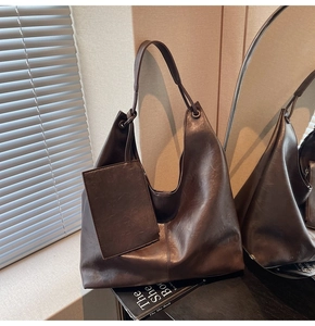 Detail of dark brown leather tote bag with small matching pouch in warm lighting