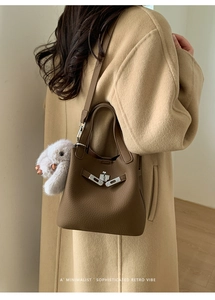 Detail of a brown lychee pattern bucket bag with silver clasp and plush rabbit charm