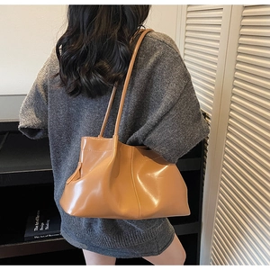 Detail showing the pleated caramel brown PU leather texture and soft tote bag structure
