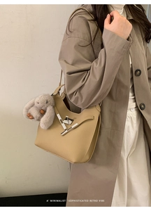 Detail of khaki leather bucket bag with silver twist lock and grey rabbit charm on model