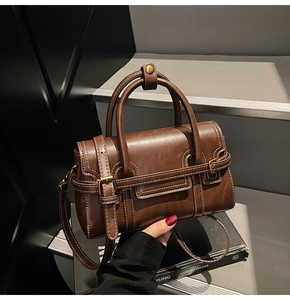 Dettaglio borsa vintage in pelle marrone con cuciture bianche e cinturini con fibbia