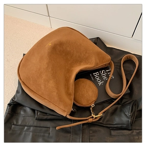 Detail view of brown suede half-moon bag with gold logo and matching mini pouch
