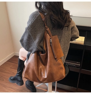 Detail of vintage brown tote bag showing wrinkled PU leather texture and small coin pouch