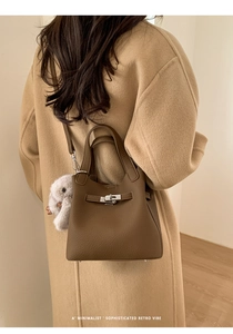 Detail view of brown lychee leather bucket bag with metal buckle and plush bunny charm