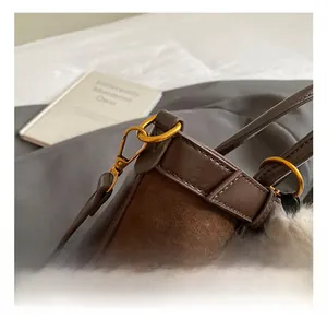 Close-up of golden hardware swivel hook and matte leather texture on brown handbag