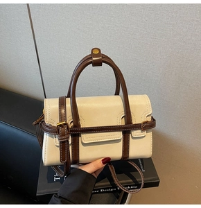 Dettaglio della borsa retrò crema con manici marroni e finiture in metallo dorato