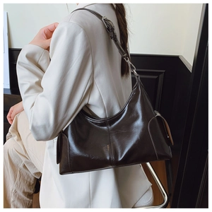 Detail of oil-waxed leather texture and adjustable strap on dark coffee hobo bag