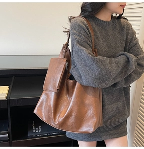 Brown tote bag with small pouch detail showing large capacity on model in gray