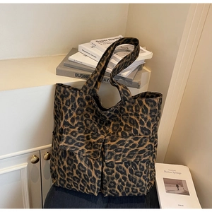 Detail of leopard print canvas tote bag featuring two front flap pockets and dual black handles