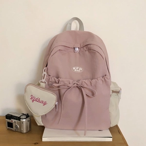 Detail eines rosa Nylon-Rucksacks mit cremefarbenen Taschen und herzförmigem Münztäschchen