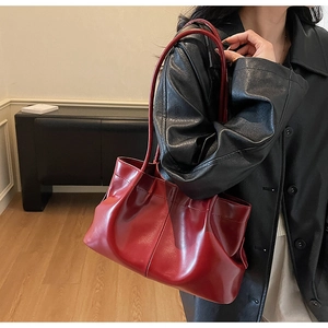 Detail of burgundy ruched tote bag with slim shoulder straps and glossy leather texture
