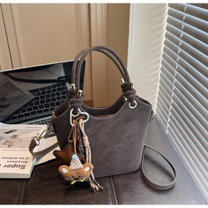 Detail of vintage brown suede bucket bag with cute bear charm and star accessories