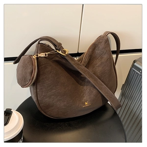 Detail of dark brown matte crescent bag with attached round coin purse on a table