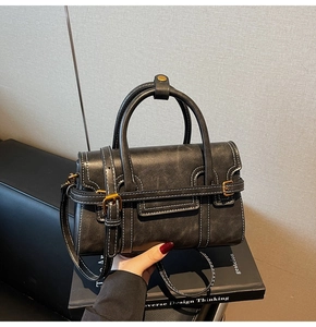 Dettaglio borsa vintage nera con cuciture bianche e fibbia in metallo dorato lucido