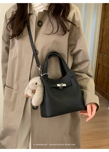 Close-up of black lychee grain leather bucket bag with silver lock and plush bunny charm