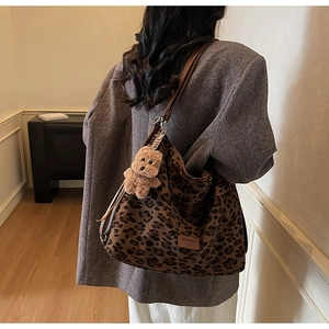 Detail of leopard print hobo tote bag with brown strap and plush bear charm decoration