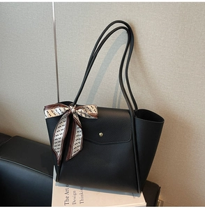 Detail of black pebbled leather tote bag with gold buckle and printed silk scarf handle