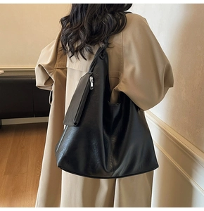Detail of a large black leather hobo bag featuring a matching mini zip pouch on side