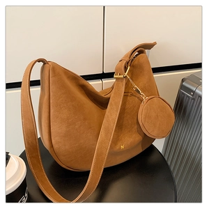 Detail view of brown matte suede bucket bag with round coin purse and gold hardware