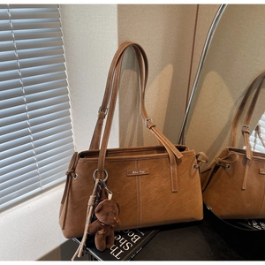 Detail of vintage brown suede tote with white stitching, plush bear charm and tassel decor