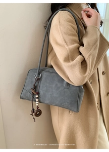 Detail of grey retro shoulder bag with matte leather texture and beaded tassel charm