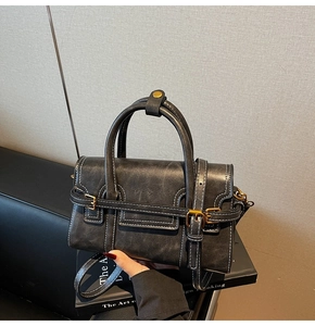 Dettaglio borsa a tracolla grigia vintage con cuciture bianche e finiture dorate