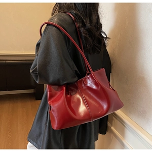 Detailed close-up of a red pleated shoulder bag showing glossy leather texture and strap