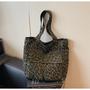 Close-up of dark green leopard print canvas tote bag with large front pockets and dual handles